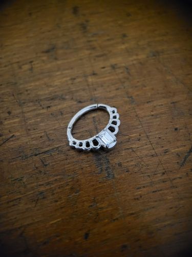 Dieser hochwertige Princess Clicker ist aus silberfarbenem Edelstahl gefertigt und besticht durch seinen wunderschönen Zirkoniastein, der Dich schon von Weitem strahlen lässt! Der Segmentring hat einen Klappverschluss, der ein einfaches Einsetzen des Piercings ermöglicht. Das Piercing ist perfekt für Dein Septum-Piercing geeignet, kann aber auch für verschiedene andere Piercings verwendet werden, wie z.B. für Ohr-Piercings oder Smiley-Piercings (Lippenbändchen).