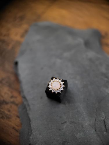 Eine Blume, die tatsächlich ewig hält! Der Delphine Aufsatz einen echten Opal als Herzstück mit wunderschönen, funkelnden CZ- Blütenblättern, die ihn umgeben.