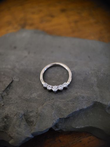 Runder Clicker in der Stärke 1.2mm. Er ist mit fünf Cubic Zircomia Steinen besetzt. Optimal für Ohrpiercings oder Septum.